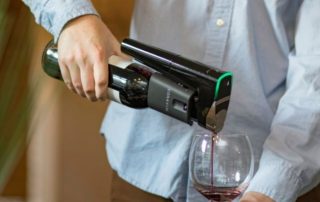 Coravin wine preservation device in hand used to pour red wine